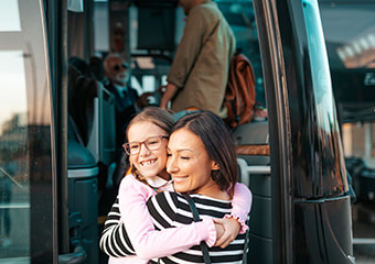 Two passengers hug as they enter a charter bus