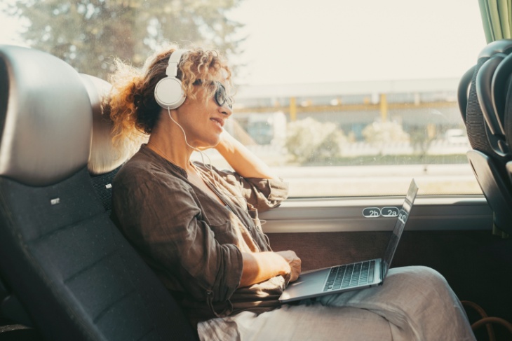 a relaxed woman watches a movie on her laptop aboard a charter bus