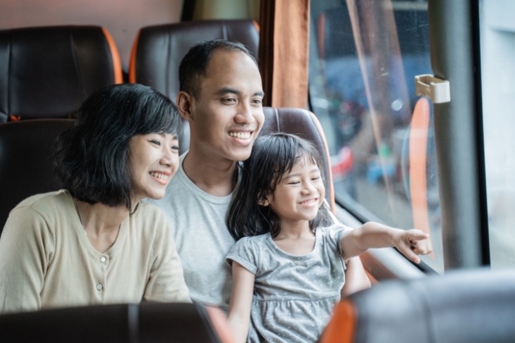 a family sits together looking out the window of a charter bus