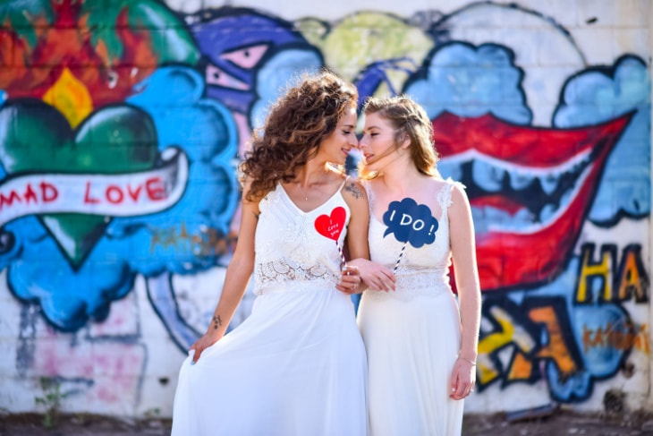 two brides smile at each other on their wedding day