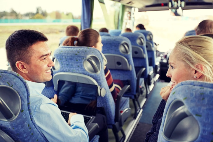 two adults smile and chat on a charter bus
