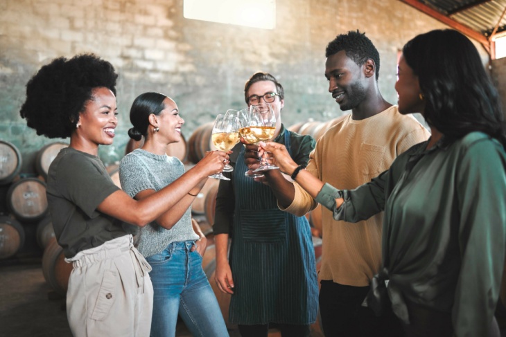 A group of friends drink wine in a wine cellar on a winery tour
